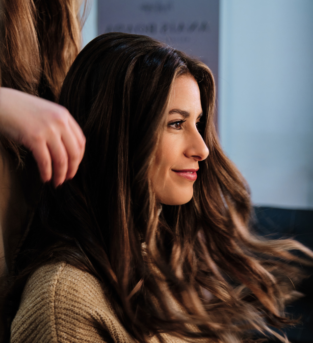 A woman receives a hairstyle makeover from another woman in a salon setting, showcasing a moment of beauty and care.